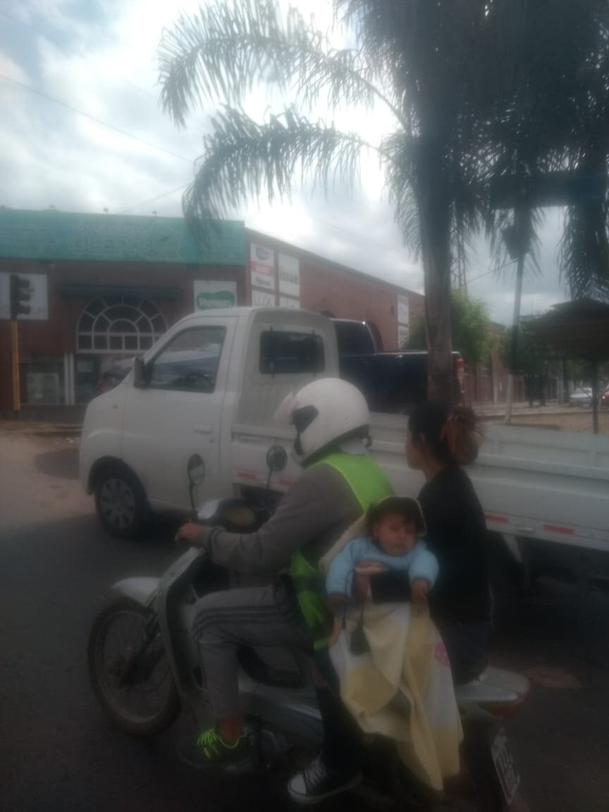 Tres personas en una moto, una mujer sin casco ni chaleco y con un ni&ntilde;o en brazos