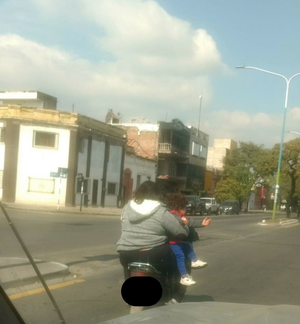 Tres personas viajan en una moto, todos sin casco ni chalecos y con un nene en brazos